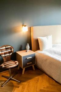 a bedroom with a bed and a chair and a nightstand at Riverside Architect-Designed Garden Apartment in Süderstapel