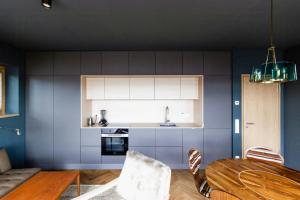 a kitchen with blue walls and a wooden table at Riverside Architect-Designed Garden Apartment in Süderstapel