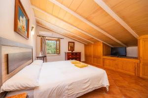 a bedroom with a white bed and a flat screen tv at Can Gallot De Punxuat - Pool in Algaida