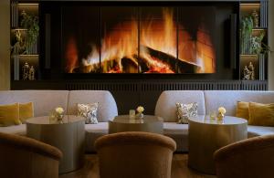 a living room with two tables and a fireplace at Leonardo Royal Hotel Munich in Munich +53 photos