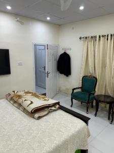 a bedroom with a bed and a green chair at Aqua pura Lodges By Ansar Qureshi in Murree