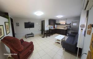 a living room with a couch and a table and a kitchen at B&B Amit 18 minutes from airport in Petaẖ Tiqwa