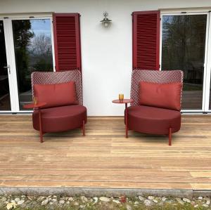 two red chairs sitting on a porch with a table at Traumhaus mit herrlichem Blick über Graz in Sankt Veit am Vogau