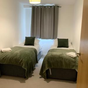 a room with two beds and a window at Spacious City Centre 2 Bedroom Apartment in Liverpool +4 photos
