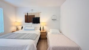 two beds in a room with white walls at Modern Luxury House 3B&4B House 30 mins DTLA in Baldwin Park