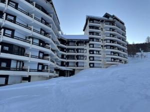 a large apartment building with snow in front of it at Très beau studio pieds des pistes tout rénové in Risoul