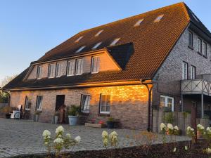 una gran casa de ladrillo con techo marrón en Ferien- und Pferdehof Egelkraut "Feriendomizil am Meer", en Wangerland