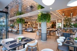 ネイポリにあるOlympic Star Beach Hotelのテーブルと椅子と植物のあるレストラン