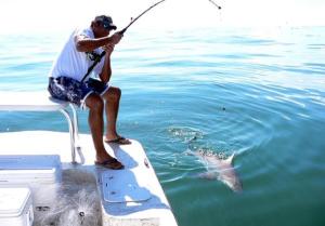 ディバにあるMusandam Starlight Dhow Cruiseの水中に魚がいるボートの上に座っている男性