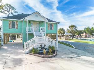 une maison verte avec une terrasse couverte blanche et des escaliers dans l'établissement Waterfront Home with Pool by Next Step Property Management, à Pass Christian