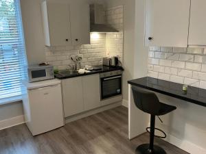 une cuisine avec des armoires blanches et un comptoir noir dans l'établissement Dublin Studio Stay, à Dublin