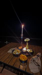 a table with three bowls of food and a candle at Aurora desert camp in Badīyah