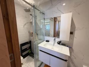 une salle de bain avec un lavabo et une douche en verre dans l'établissement Apartement charmante amira, à Oulad Kerroum 30 autres photos