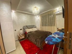 - une petite chambre avec un lit et un lustre dans l'établissement Apartement charmante amira, à Oulad Kerroum