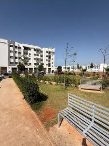 un banc blanc dans un parc à côté d'un bâtiment dans l'établissement Apartement charmante amira, à Oulad Kerroum