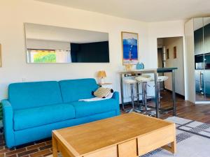 a living room with a blue couch and a table at Le bleu de George Sand, vue mer exceptionnelle in La Seyne-sur-Mer