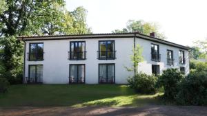 a white house with black windows on a yard at Heidenauer Hotel im Park in Heidenau
