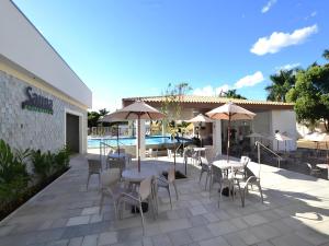 a patio with tables and chairs and umbrellas next to a pool at Resort Internacional DiRoma in Caldas Novas +12 photos