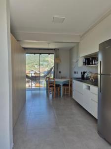 a kitchen and dining room with a table and refrigerator at VerdeMar Loft - Gamboa Beach - SC in Garopaba