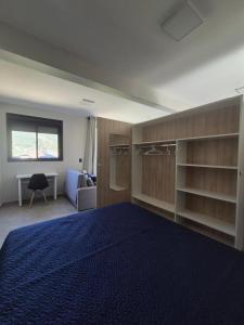 a bedroom with a blue bed and a desk at VerdeMar Loft - Gamboa Beach - SC in Garopaba