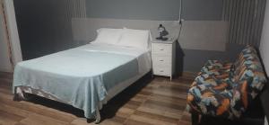 1 dormitorio con 1 cama y mesita de noche con 1 cama blanca en La casita de Issa via Boquete, en David