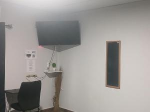 Una habitación con una silla y un televisor en una pared. en La casita de Issa via Boquete, en David