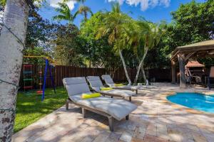 a backyard with two lounge chairs and a pool at Family Oasis at Sunrise Private Pool, Game, Cardio, Grill, Work & Play in Sunrise