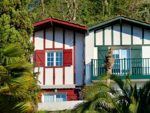 a building with red and blue windows and trees at Les Collines Iduki in Labastide-Clairence