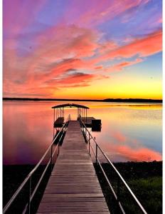a dock with a boat on the water at sunset at Bluebird Sanctuary w Stunning Sunset Views Sleeps 28 in Big Sandy