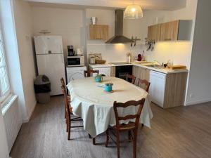 a kitchen with a table with chairs and a refrigerator at Fenêtres sur Mer Arromanches in Arromanches-les-Bains +13 photos