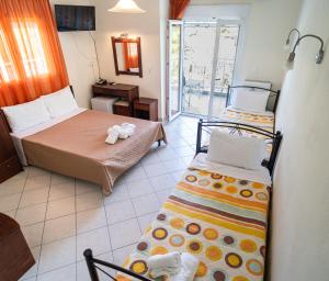 a bedroom with two beds and a door to a balcony at Hotel Kastri in Nea Mesangala