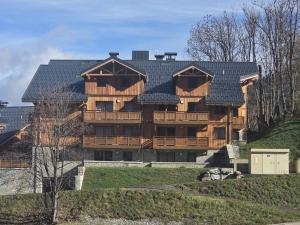 ein großes Holzgebäude mit schwarzem Dach in der Unterkunft T2 neuf à Valmorel, 4 pers, parking - FR-1-291-1040 in Valmorel