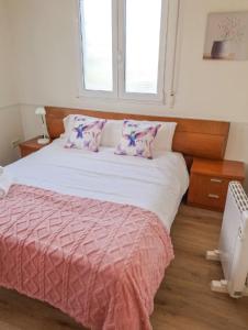 メリーデにあるCarmela Houseのピンクのシーツが敷かれたベッドと窓のある寝室