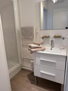 a white bathroom with a sink and a shower at Fenêtres sur Mer Arromanches in Arromanches-les-Bains