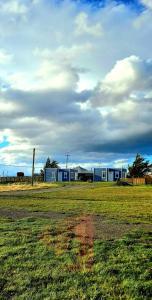 a field of grass with buildings in the background at Cabañas Frange in Puerto Natales