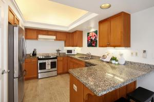 a kitchen with wooden cabinets and stainless steel appliances at Villas of Kamalii #35 in Princeville