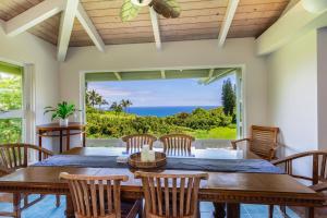 a dining room with a table and chairs and a large window at Wai Lani in Princeville