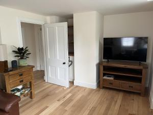 a living room with a flat screen tv on a entertainment center at The Butler's Flat at Solsgirth Home Farm in Dollar