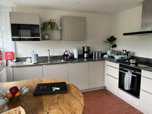 a kitchen with white cabinets and a wooden table at The Butler's Flat at Solsgirth Home Farm in Dollar