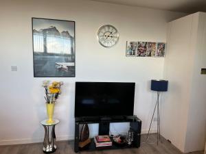 a living room with a tv and a vase with flowers at 2 Bedroom Flat Sun in town Center Wellingborough in Wellingborough