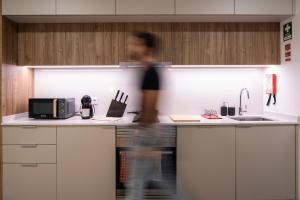 a person is walking in a kitchen at Color Avenida T0 in Águeda +24 photos