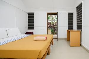 ein Schlafzimmer mit einem Bett mit gelber Tagesdecke in der Unterkunft SAVITHRI Inn COTTAGE in Varkala