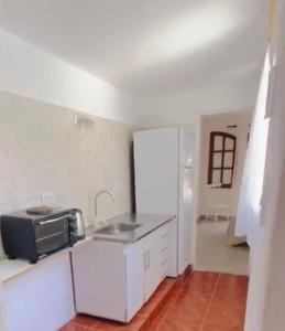 サンベルナルドにあるColonial suitesのシンクと電子レンジを備えた白いキッチン