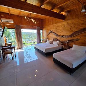 a bedroom with two beds and a wooden wall at Tupa Lodge in Puerto Iguazú