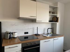 Una cocina con gabinetes blancos y un fregadero. en LIBORIA I Über den Dächern Augsburgs, en Augsburg