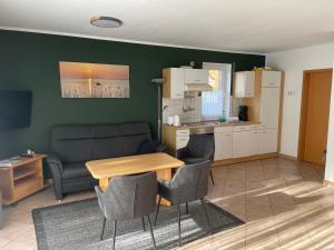 un salon avec une table et un canapé et une cuisine dans l'établissement Ferienwohnungen Wiek, Haus Luv & Lee, à Wiek auf Rügen
