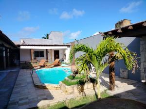a house with a swimming pool and a palm tree at Casa confortável c piscina, lazer e espaço gourmet in Barra de São Miguel