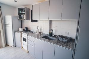 a white kitchen with a sink and a refrigerator at Check and home - Chapa II - 4 huéspedes con patio y parrilla in Chapadmalal