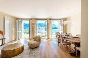 a dining room with a table and chairs and windows at Residenza di Luce - by MyHomeInComo in Griante Cadenabbia