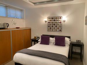 Un dormitorio con una cama grande con almohadas moradas. en NELL GWYNN HOUSE - Hotel Style POD Room 62, en Londres